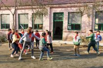 Сельская учительница и счастливые ученики играют вместе на школьном дворе — стоковое фото