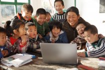 Сельская учительница и ученики вместе используют ноутбук в школе — стоковое фото