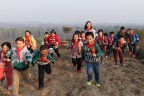 Young female teacher and chinese school students playing in rural area — Stock Photo
