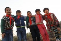 Low angle view of happy chinese pupils standing together and smiling at camera outdoor — Stock Photo