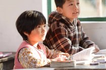 Chinesische Grundschüler sitzen in ländlicher Schule am Schreibtisch — Stockfoto