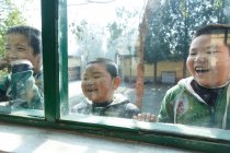 Grundschüler blicken durch Fenster in Grundschulgebäude — Stockfoto