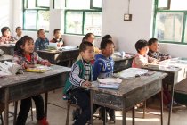 Étudiants chinois assis aux bureaux et étudiant dans une école primaire rurale — Photo de stock