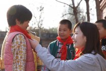 Professor chinês rural e alunos em cachecóis vermelhos no pátio da escola — Fotografia de Stock
