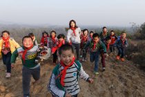 Junge Lehrerin und chinesische Schüler auf dem Land spielen im Freien — Stockfoto