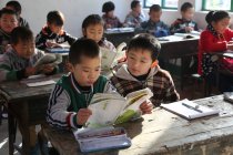 Étudiants chinois qui étudient avec des manuels scolaires dans une école primaire rurale — Photo de stock
