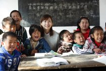 Feliz chinês rural feminino professor e alunos em sala de aula — Fotografia de Stock