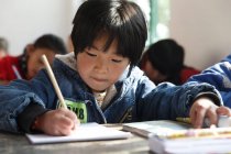 Étudiants chinois du primaire écrivant en classe dans une école rurale — Photo de stock