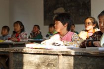 Китайские школьники сидят за партами и учатся в сельской начальной школе — стоковое фото