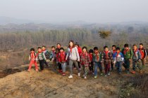 Joven profesora y estudiantes de escuela rural china jugando al aire libre - foto de stock