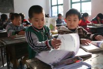Estudiantes de escuelas chinas que estudian con libros de texto en la escuela primaria rural - foto de stock