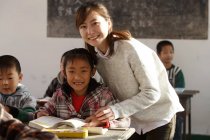 Happy chinese rural female teacher and pupils in classroom — Stock Photo