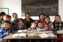 Insegnante femminile cinese rurale e alunni che sorridono alla telecamera in classe — Foto stock