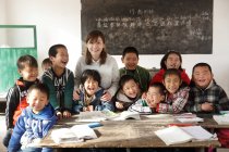 Китайская сельская учительница и ученики улыбаются перед камерой в классе — стоковое фото