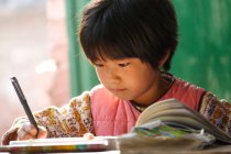 Орієнтована Китайська школярка навчається на столі в сільській початкової школи — стокове фото