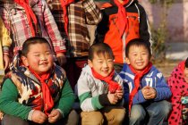 Щасливі сільські китайські учні посміхаються на камеру на відкритому повітрі, обрізаний постріл — стокове фото