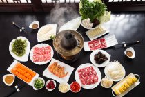 Vista ad alto angolo della pentola di carne di montone con deliziosi ingredienti in tavola — Foto stock