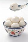Vista de cerca de la cuchara de porcelana y tazón con bolas de arroz glutinoso en blanco - foto de stock