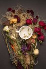 Vue de dessus de belles diverses fleurs séchées disposées et tasse — Photo de stock