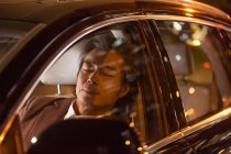 Втомлений зрілий азіатський бізнесмен спить в машині вночі — стокове фото