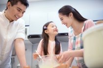 Vista basso angolo di felice famiglia asiatica con un bambino che cucina insieme in cucina — Foto stock