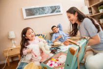 Happy parents with adorable little daughter packing suitcase on bed — Stock Photo