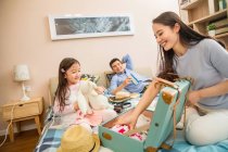 Glückliche Eltern mit entzückender kleiner Tochter beim Kofferpacken im Bett — Stockfoto