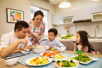 Счастливая азиатская семья с двумя детьми, обедающими вместе дома — стоковое фото