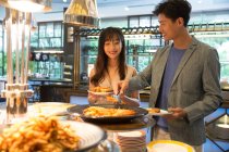 Happy young asian couple choosing delicious food in buffet — Stock Photo