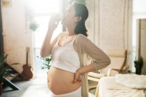 Side view of happy young pregnant woman eating apple at home — Stock Photo