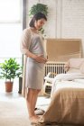 Felice giovane donna incinta in piedi in camera da letto e toccante pancia — Foto stock