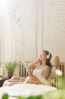 Young pregnant chinese woman in headphones resting in chair and using digital tablet at home — Stock Photo