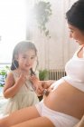 Adorable child with stethoscope playing with pregnant mother — Stock Photo