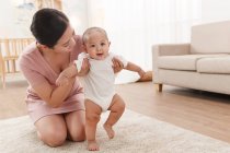 Junge Mutter trägt entzückendes Kleinkind auf Teppich — Stockfoto