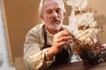 Focado homem maduro fazendo modelo de veleiro na oficina — Fotografia de Stock