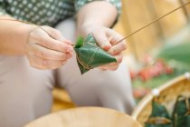 Close-up partial view of woman making traditional chinese dish zongzi — Stock Photo