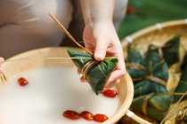 Teilansicht einer Frau mittleren Alters, die traditionelles chinesisches Gericht Zongzi zubereitet — Stockfoto