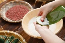 Abgeschnittene Aufnahme einer Frau mittleren Alters, die traditionelles chinesisches Gericht zongzi zubereitet — Stockfoto