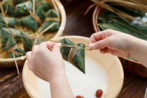 Ritagliato colpo di donna di mezza età rendendo piatto tradizionale cinese zongzi — Foto stock