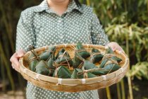 Cropped shot of middle-aged woman holding basket with zongzi — Stock Photo