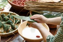Close-up partial view of middle-aged woman making zongzi — Stock Photo