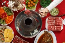 Abgeschnittene Aufnahme von Menschen, die Essstäbchen in der Hand halten und leckeres Hot-Pot-Essen essen — Stockfoto
