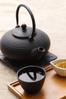 Чорний керамічний чайник і чашка чаю на дерев'яному лотку — стокове фото