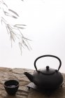Крупный план керамического чайника и чашки на каменной поверхности на белом — стоковое фото