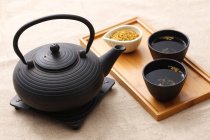 Hochwinkelblick auf schwarze Keramik-Teekanne und Tassen Tee auf Holztablett — Stockfoto
