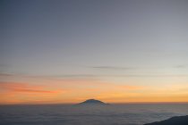 Повітряний вид на величний гірський пік у хмарах під час мальовничого сходу сонця — стокове фото