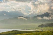 Дивовижний гірський пейзаж з бунгало на зеленому схилі, водоймою і лісом в хмарний день — стокове фото