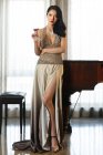 Mode femme sexy appuyé contre le piano — Photo de stock