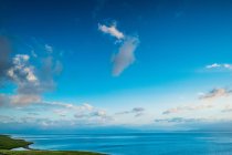 Costa verde e majestoso corpo de água sob o céu azul com nuvens no dia ensolarado — Fotografia de Stock
