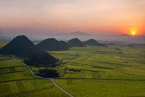 Дивовижний краєвид з мальовничими пагорбами і зеленими полями під час сходу сонця, вид з повітря — стокове фото